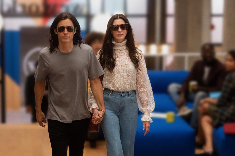 Jared Leto und Anne Hathaway gehen Händchen haltend durch einen modernen Büroraum.