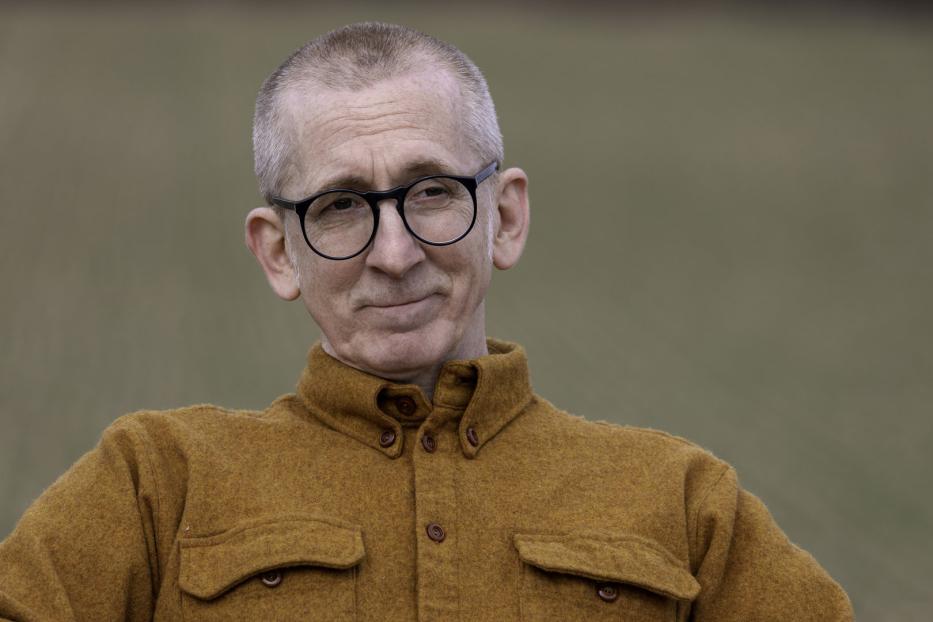Ein Mann mit Brille und braunem Hemd blickt in die Ferne.