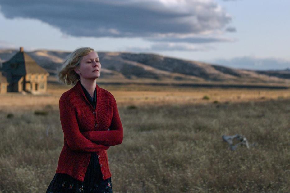 Kirsten Dunst steht mit geschlossenen Augen in einem Feld vor einem Haus.