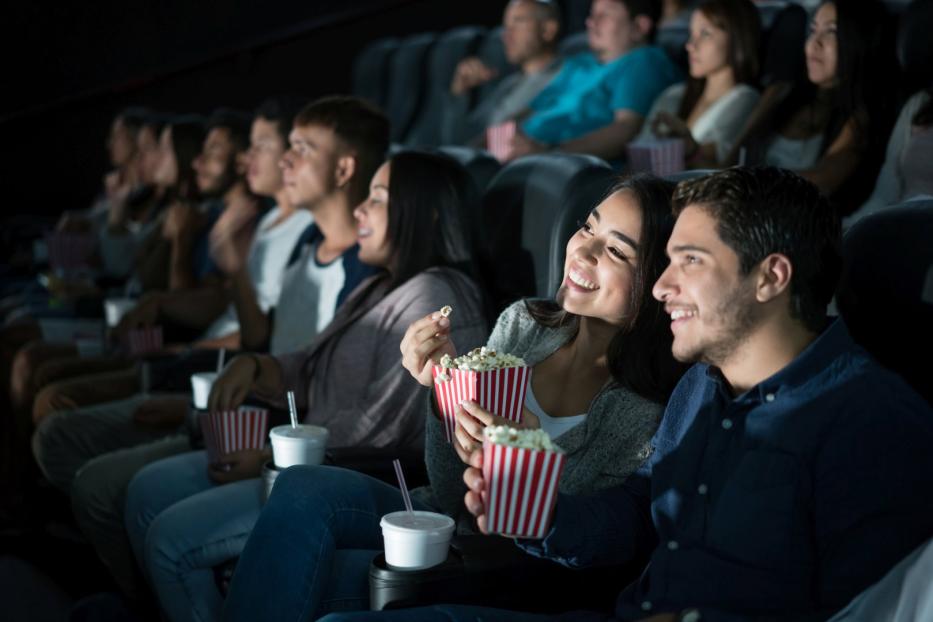 Ein junges Paar schaut im Kino einen Film und isst Popcorn.