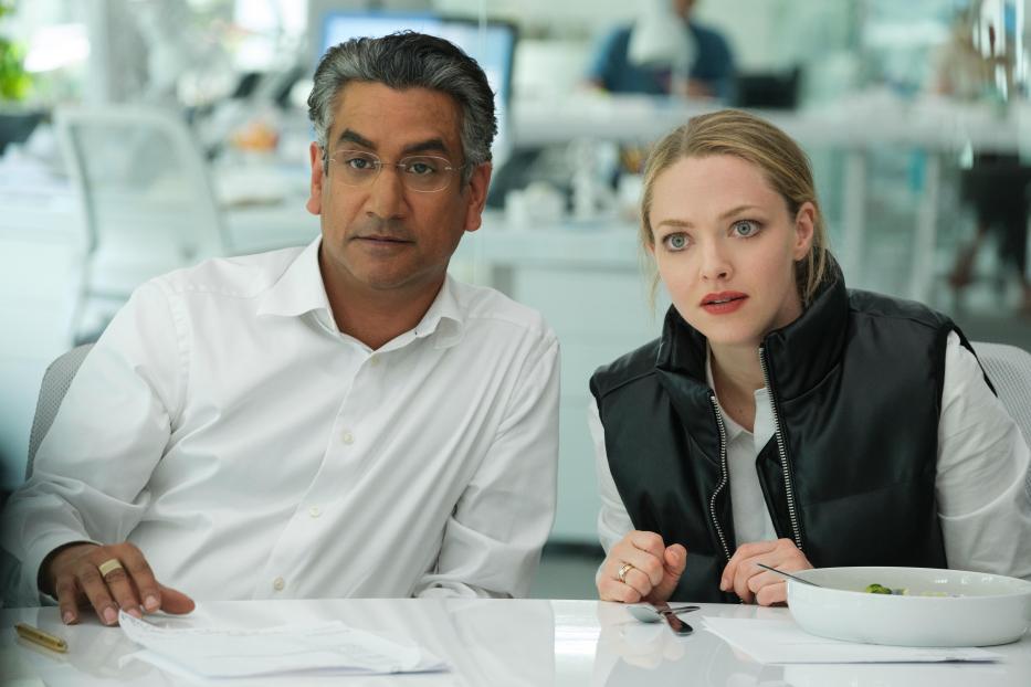 Ein Mann und Amanda Seyfried sitzen an einem Tisch in einem Büro.