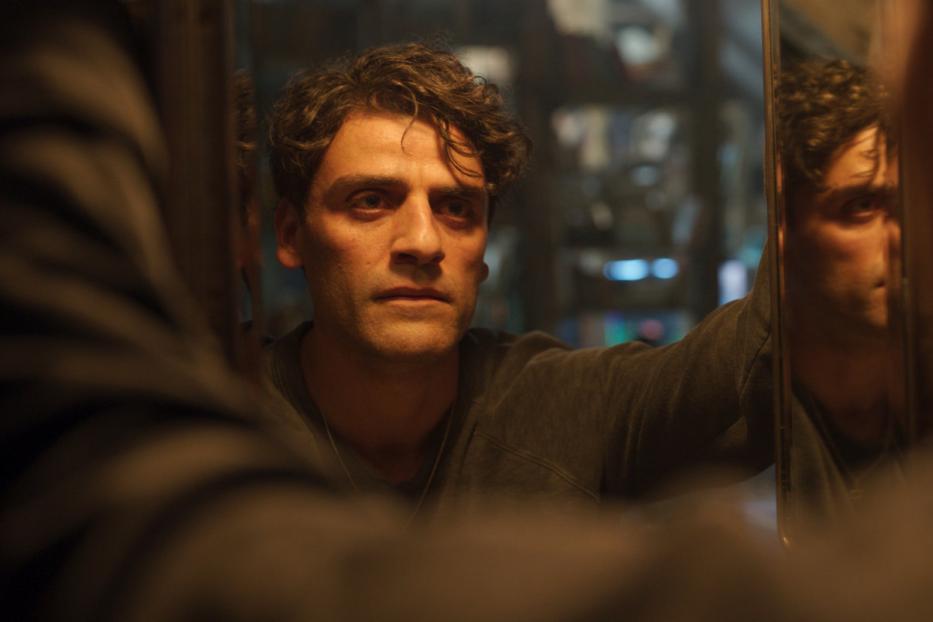 Oscar Isaac blickt in einem dunklen Raum in einen Spiegel.