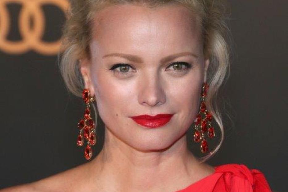 Malin Åkerman trägt ein rotes Kleid und rote Ohrringe.