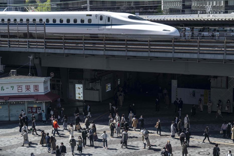 Ein Shinkansen-Hochgeschwindigkeitszug fährt über eine belebte Straße in Japan.