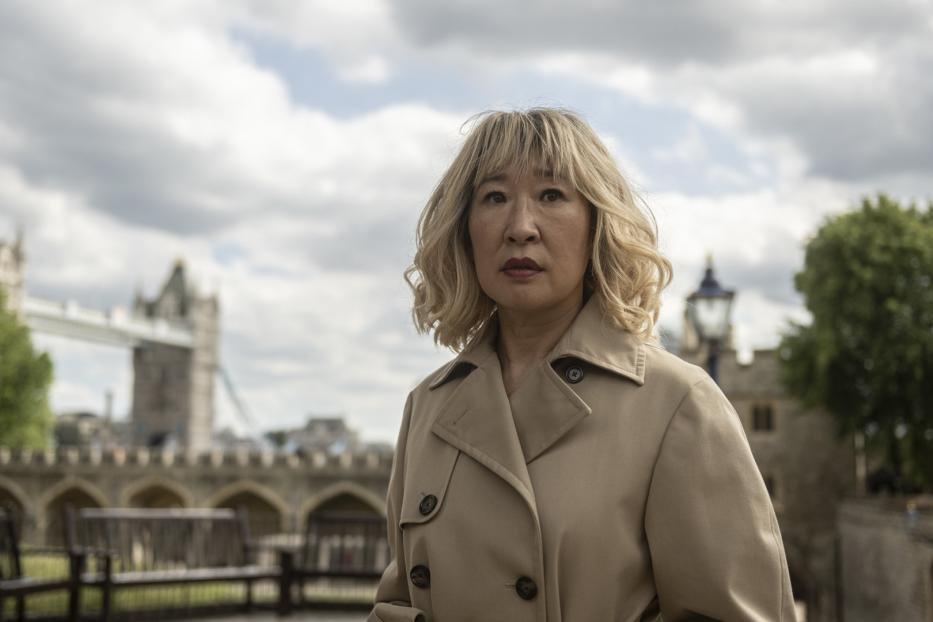 Sandra Oh vor dem Tower of London, gekleidet in einem Trenchcoat.