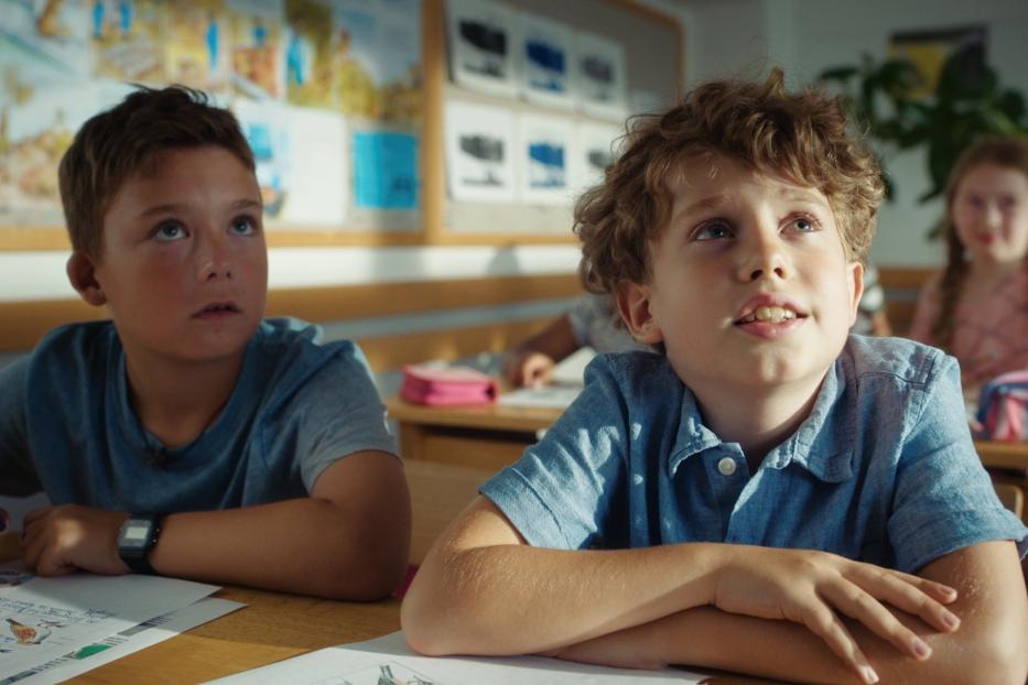 Zwei Jungen sitzen in einem Klassenzimmer und schauen nach oben.