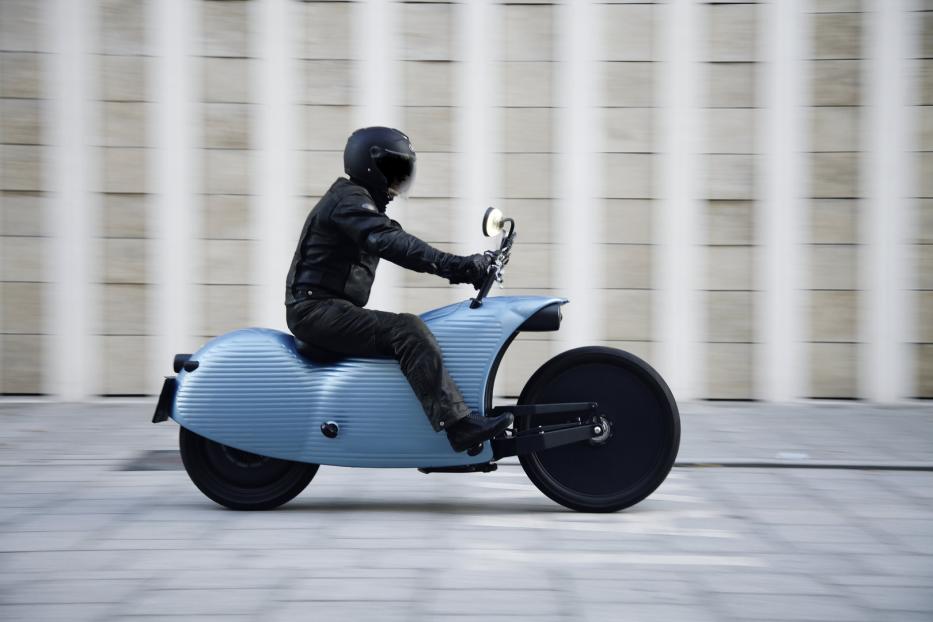 Ein Fahrer auf einem blauen Johammer J1 Motorrad vor einer Wand.