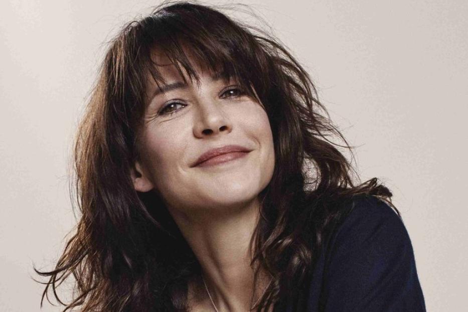 Sophie Marceau lächelt mit verschränkten Armen in die Kamera.