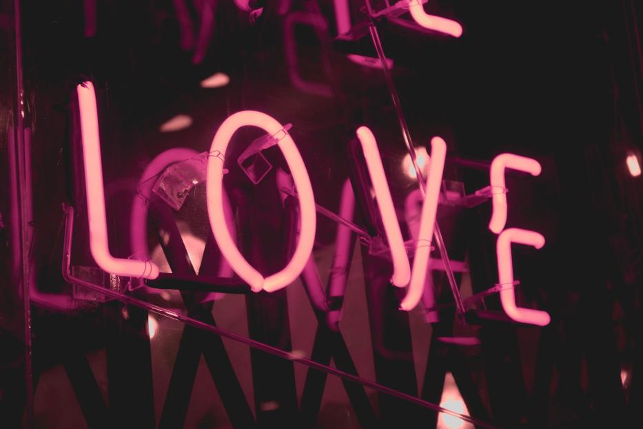 Ein rosafarbenes Neonlicht formt das Wort „Love“.