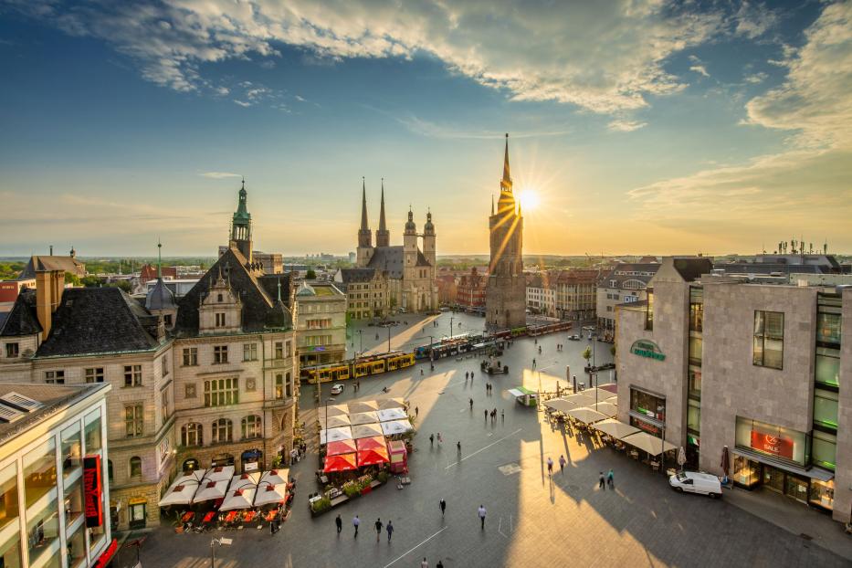 Blick auf den Marktplatz von Halle (Saale) mit der Marktkirche und Passanten im Abendlicht.