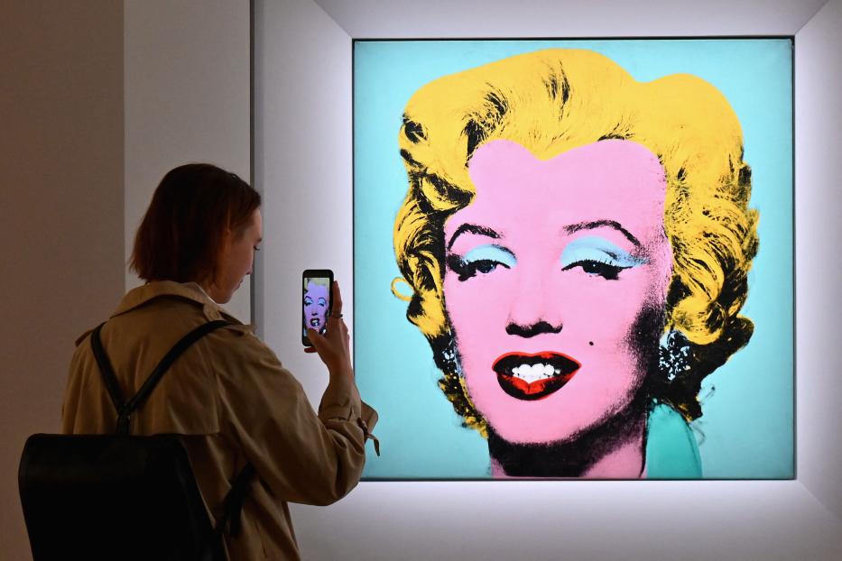 Eine Frau fotografiert Andy Warhols „Marilyn“-Gemälde mit ihrem Smartphone.