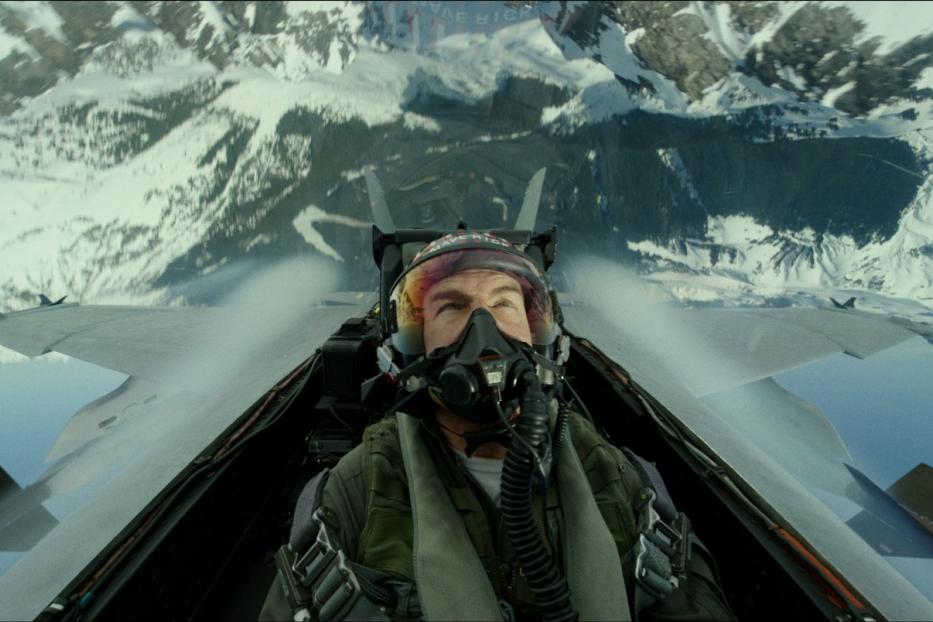Tom Cruise als Pilot in einem Kampfjet über schneebedeckten Bergen.