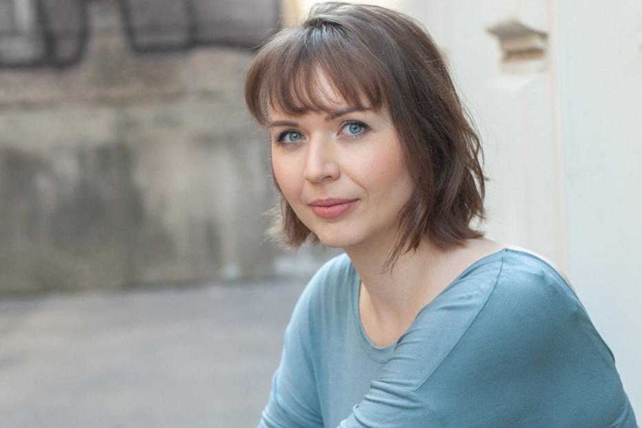 Porträt einer Frau mit braunen Haaren und blauen Augen.