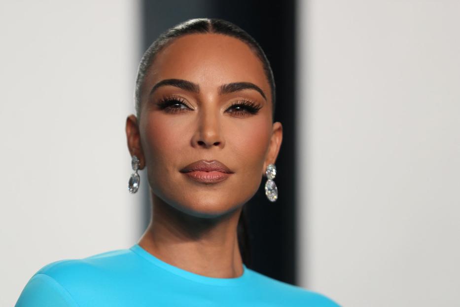 Porträt von Kim Kardashian mit blauem Oberteil und auffälligen Ohrringen.