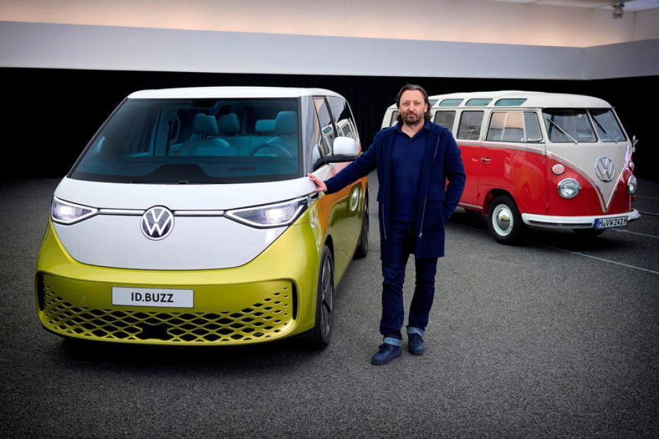 Ein Mann steht neben einem gelb-weißen VW ID.Buzz, im Hintergrund ein roter VW Bulli.