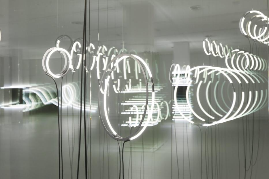 Kreisförmige Neonröhren hängen von der Decke und bilden eine Installation.