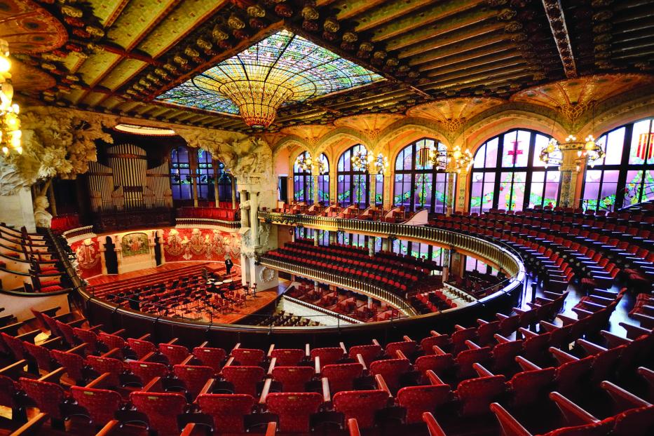 Der Palau de la Música Catalana in Barcelona mit rotem Gestühl und einem Buntglasfenster in der Decke.