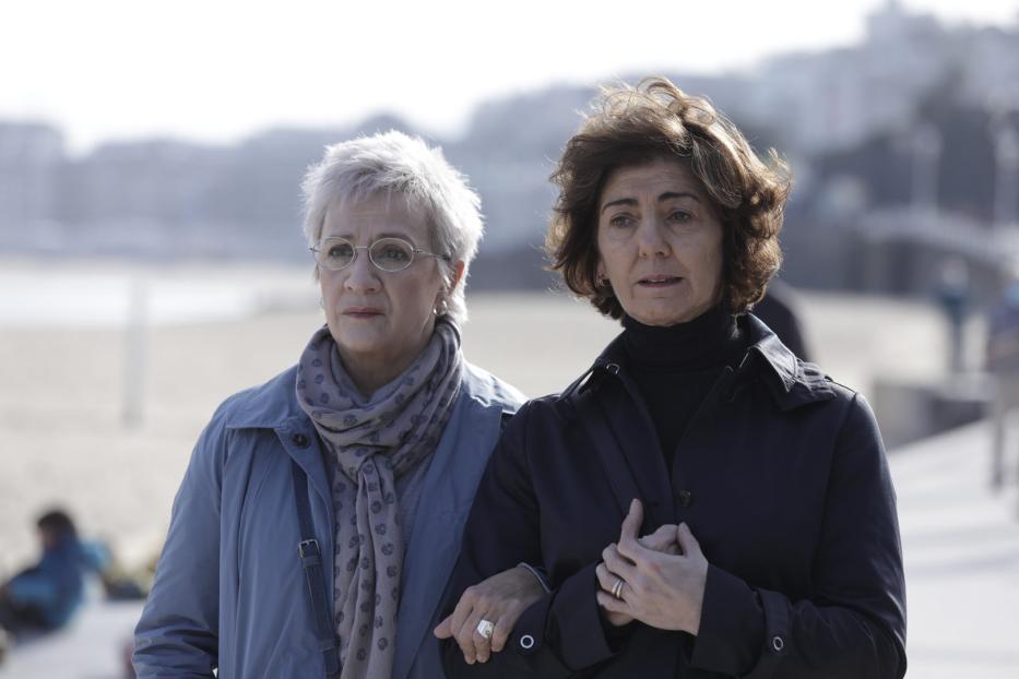 Zwei Frauen mittleren Alters gehen am Strand spazieren.