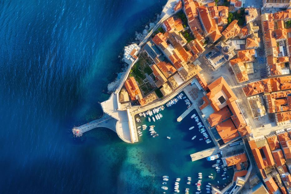 Luftaufnahme von Dubrovnik, Kroatien, mit roten Dächern und einem Hafen voller Boote.