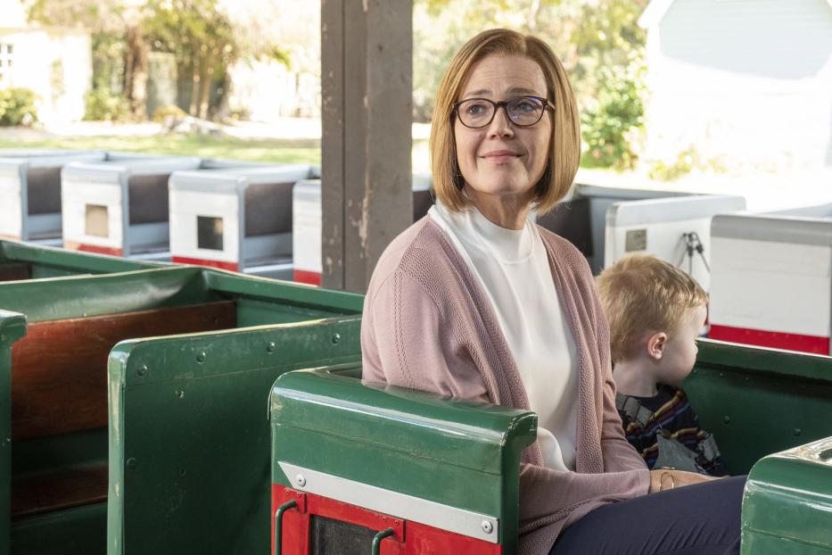 Eine Frau mit Brille und ein Kind sitzen in einem grünen Zug.