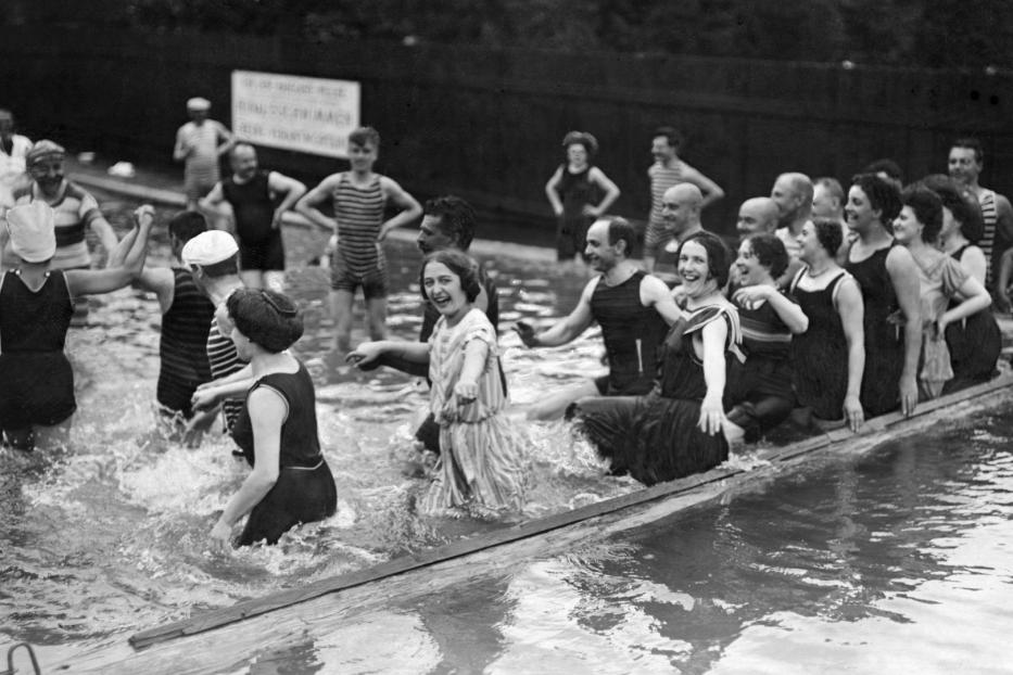 Eine Gruppe von Menschen in Badebekleidung vergnügt sich im Wasser.