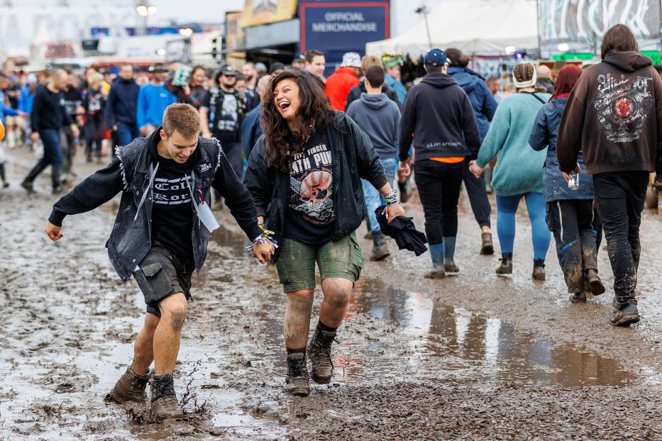 Besucher laufen schlammbedeckt beim Nova Rock Festival 2022.