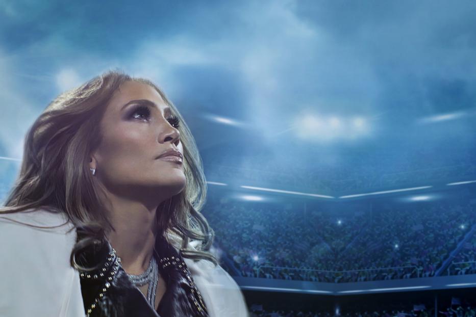 Jennifer Lopez blickt in einem Stadion voller Menschen nach oben.