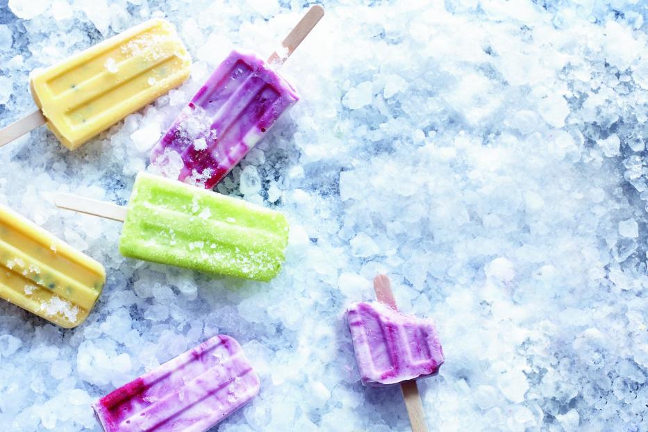 Mehrfarbige Eis am Stiel liegen auf zerstoßenem Eis.