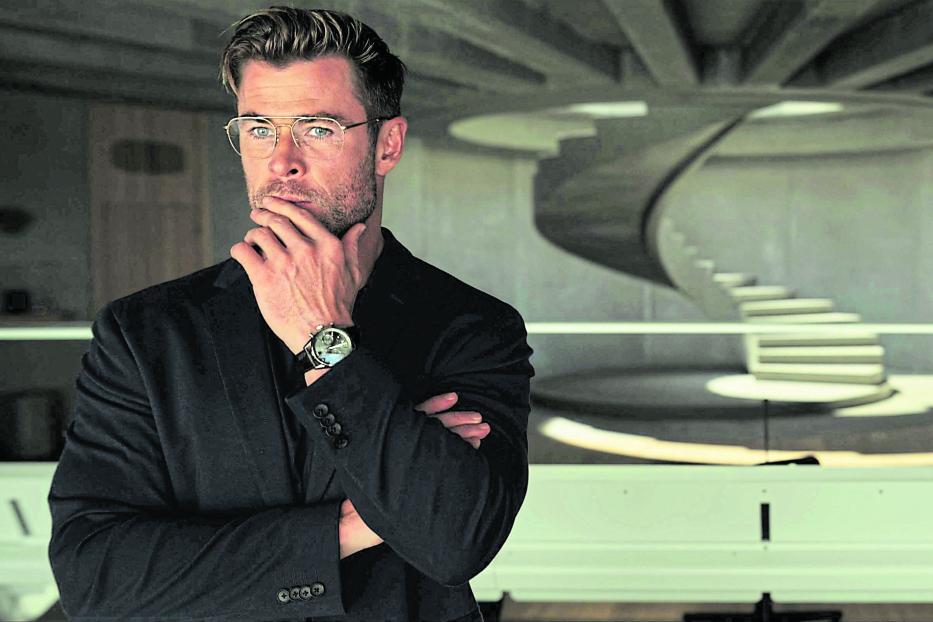 Chris Hemsworth steht in einem modernen Raum mit einer Wendeltreppe.