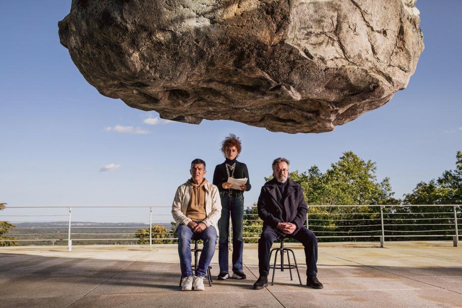 Penélope Cruz, Antonio Banderas und José Luis Gómez sitzen unter einem riesigen Felsen.