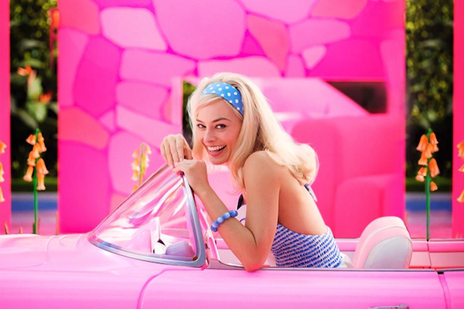 Margot Robbie als Barbie in einem pinkfarbenen Chevrolet Corvette Cabriolet.