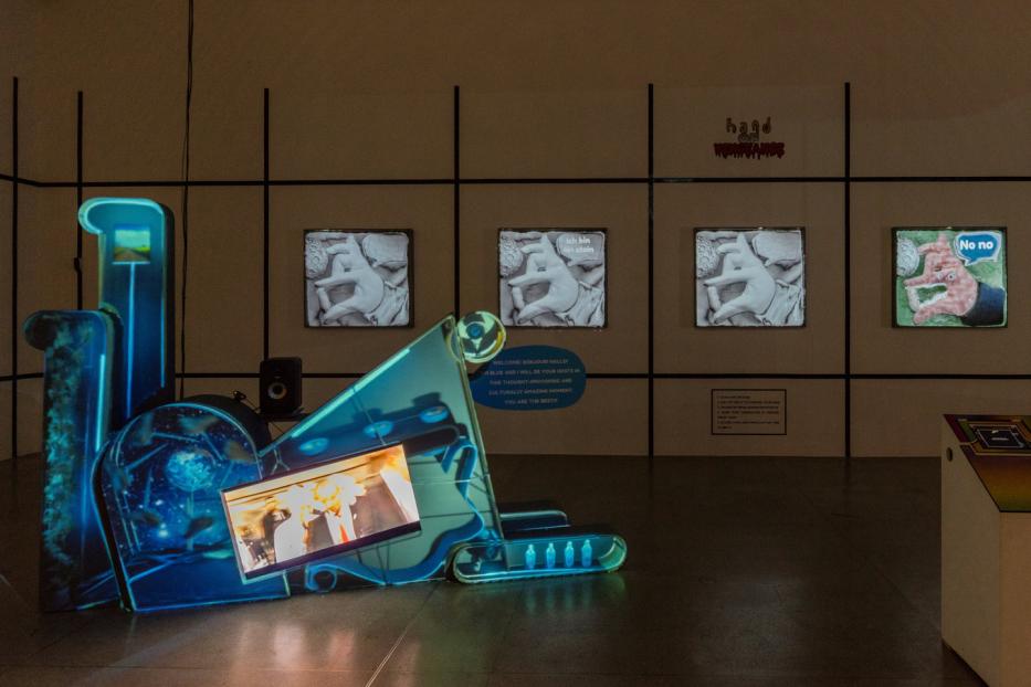 Eine Kunstinstallation mit Bildschirmen und blauer Beleuchtung in einem Ausstellungsraum.