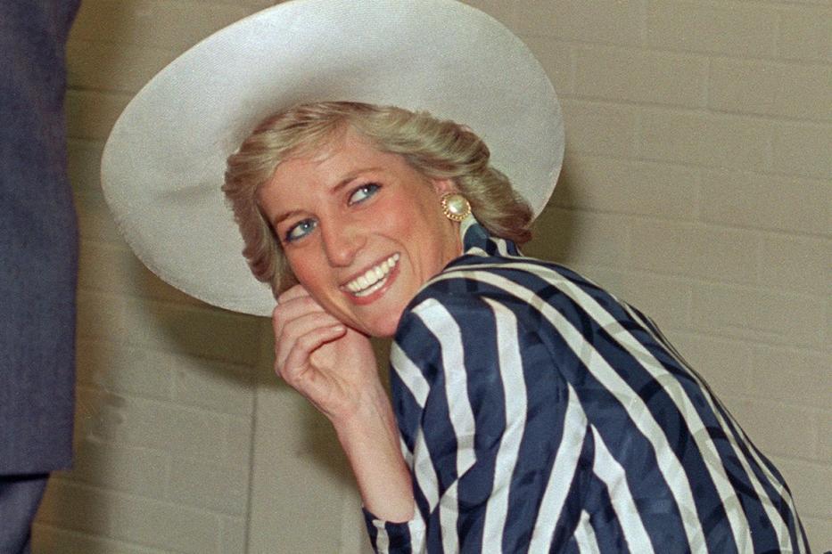 Prinzessin Diana lächelt mit einem gestreiften Blazer und einem Hut.