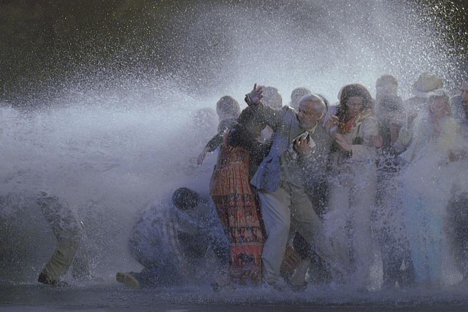 Eine Gruppe von Menschen wird von einem starken Wasserstrahl getroffen.