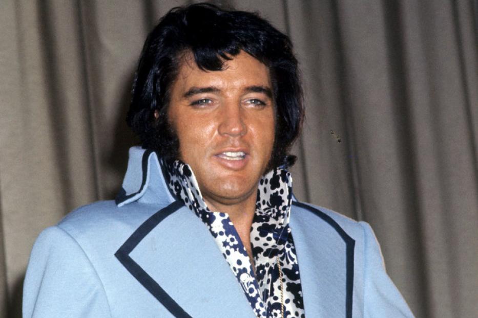 Elvis Presley in einem hellblauen Anzug mit einem auffälligen Hemd.