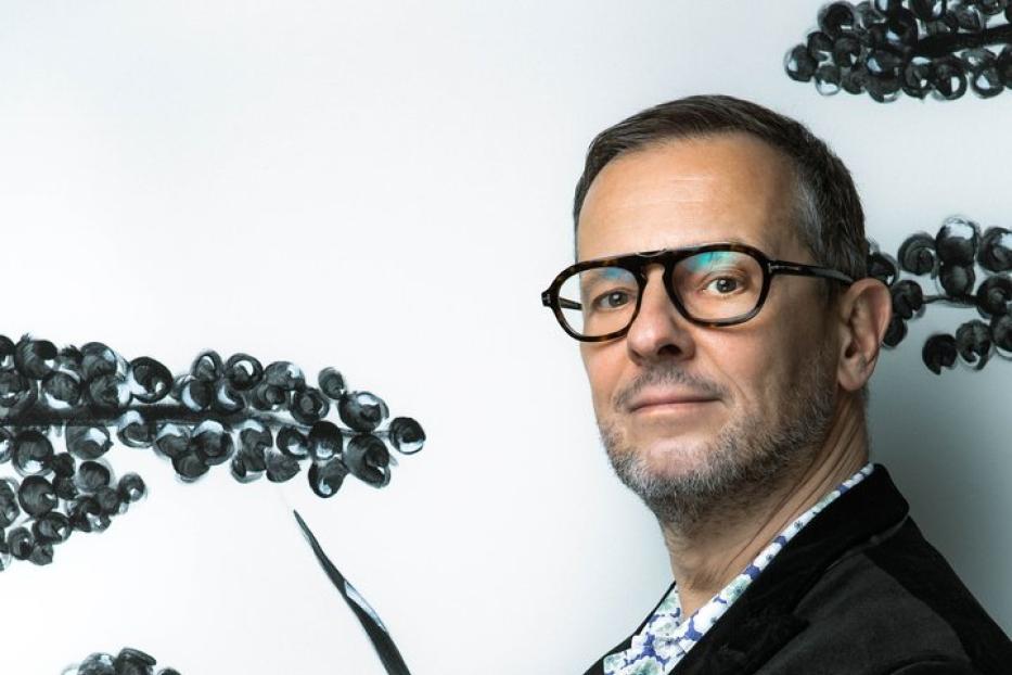 Ein Mann mit Brille hält einen kleinen orangefarbenen Ball in seinen Händen.