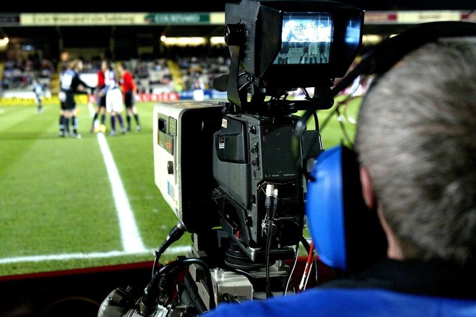 Ein Kameramann filmt ein Fußballspiel im Stadion.