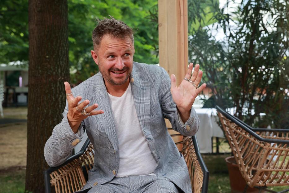 Ein Mann in einem karierten Anzug gestikuliert im Freien.