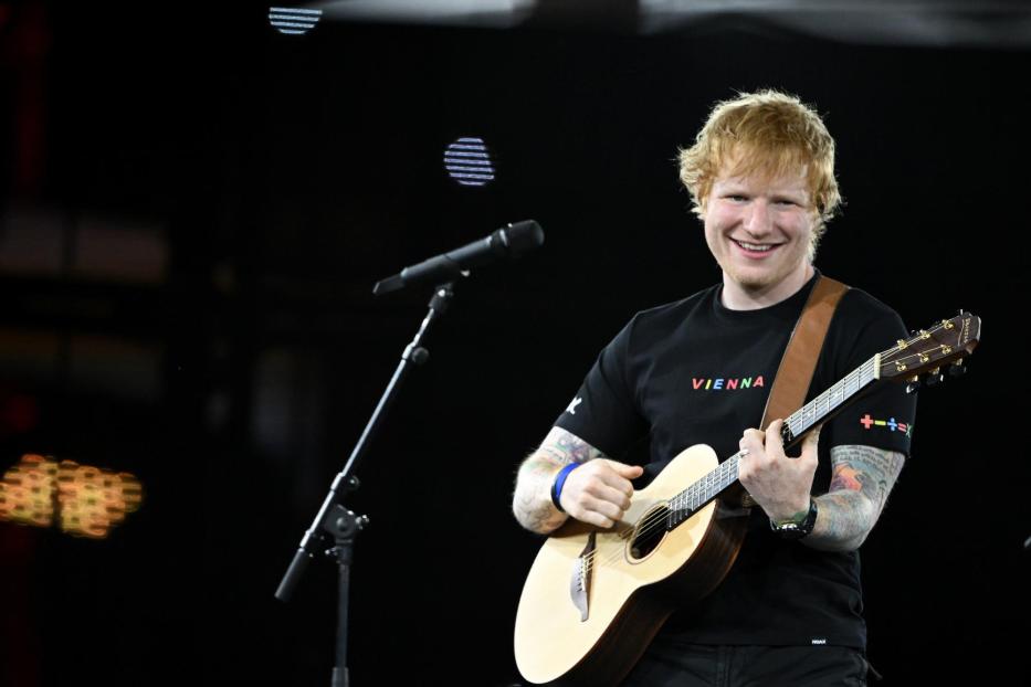 Ed Sheeran tritt mit seiner Gitarre auf einer Bühne auf.