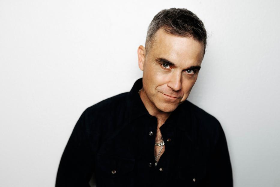 Porträt von Robbie Williams vor einem weißen Hintergrund.