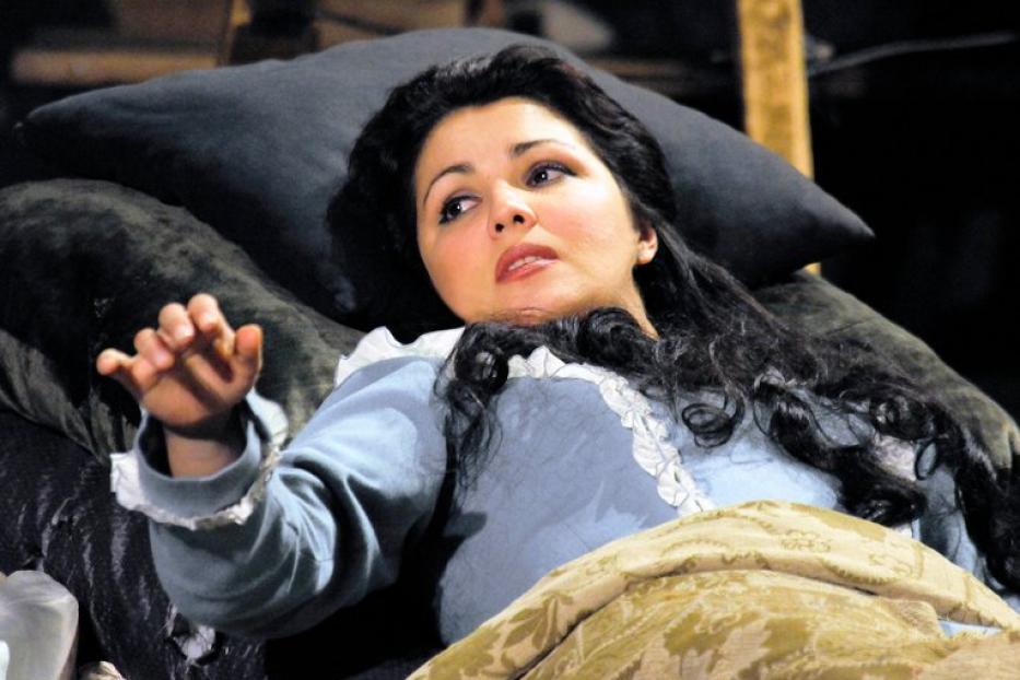 Eine Frau liegt in einem hellblauen Kleid auf einem Bett und blickt nach oben.