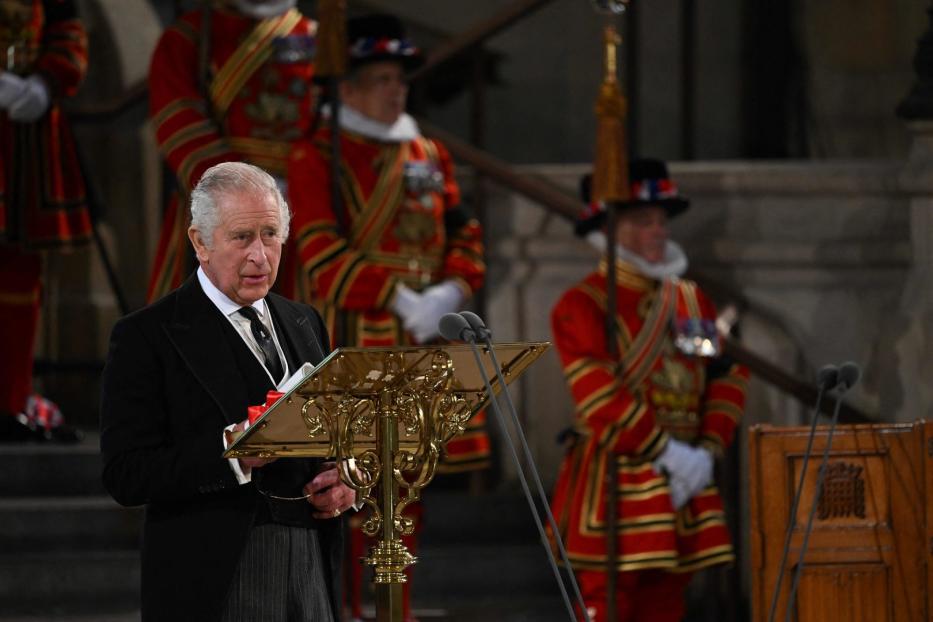 König Charles III. hält eine Rede vor Leibwächtern in traditioneller Kleidung.