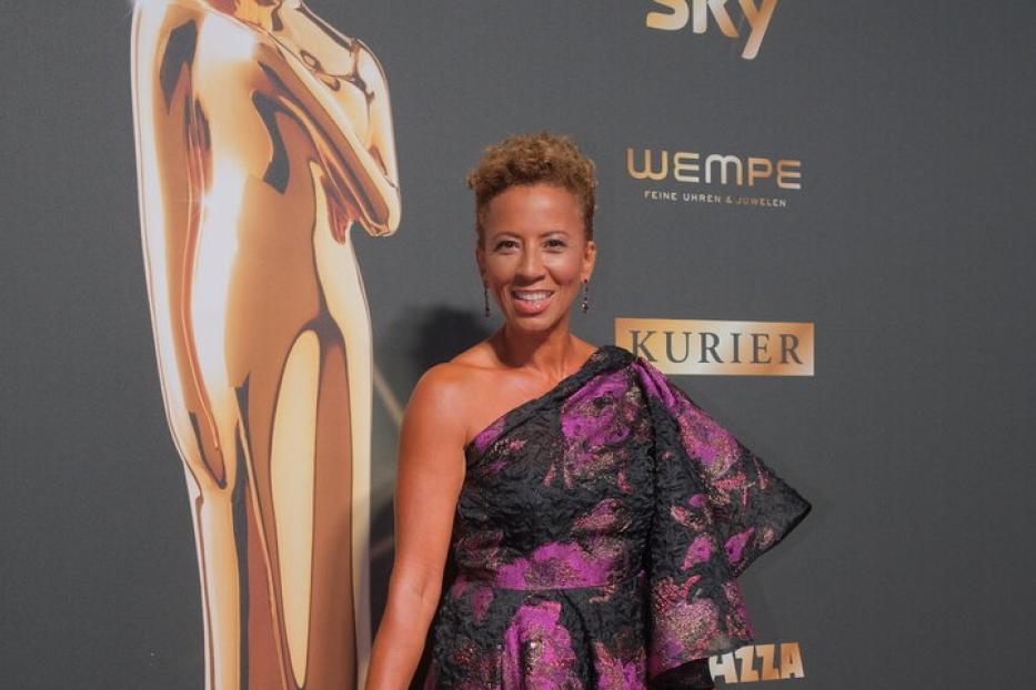 Eine Frau in einem schulterfreien, blumengemusterten Kleid auf dem roten Teppich.