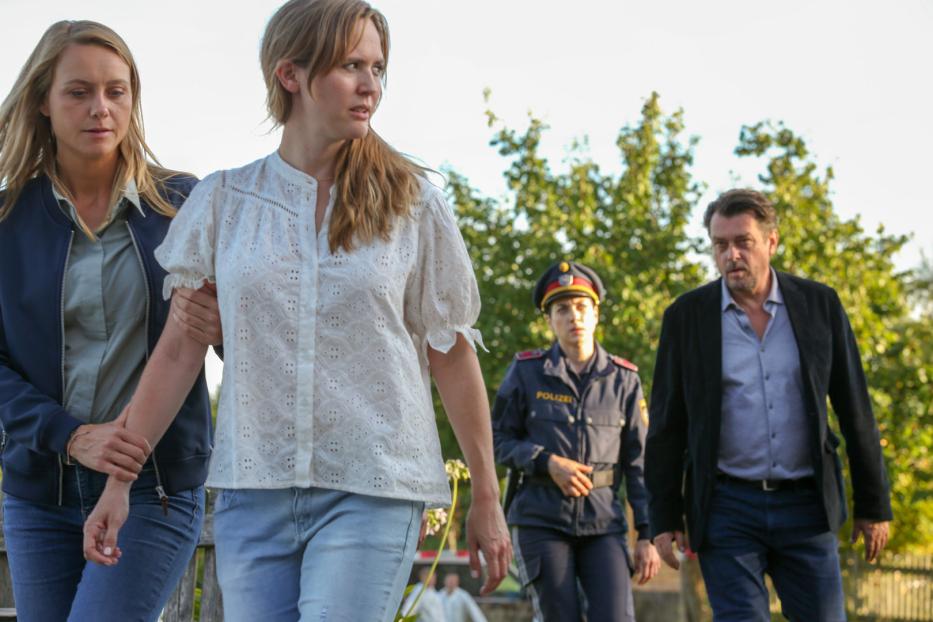 Zwei Frauen werden von einem Mann und einer Polizistin begleitet.
