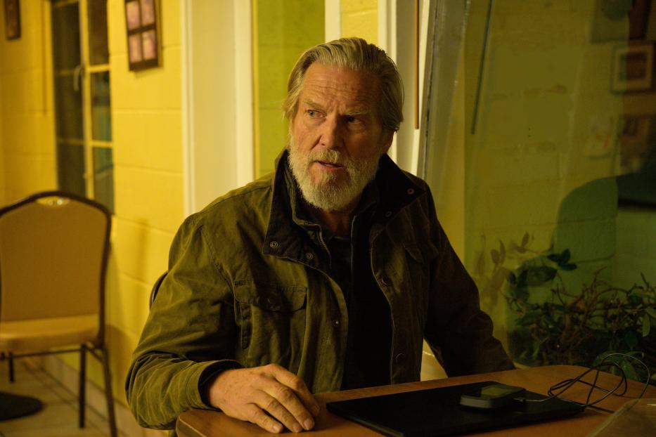 Jeff Bridges sitzt an einem Tisch mit einem Laptop.