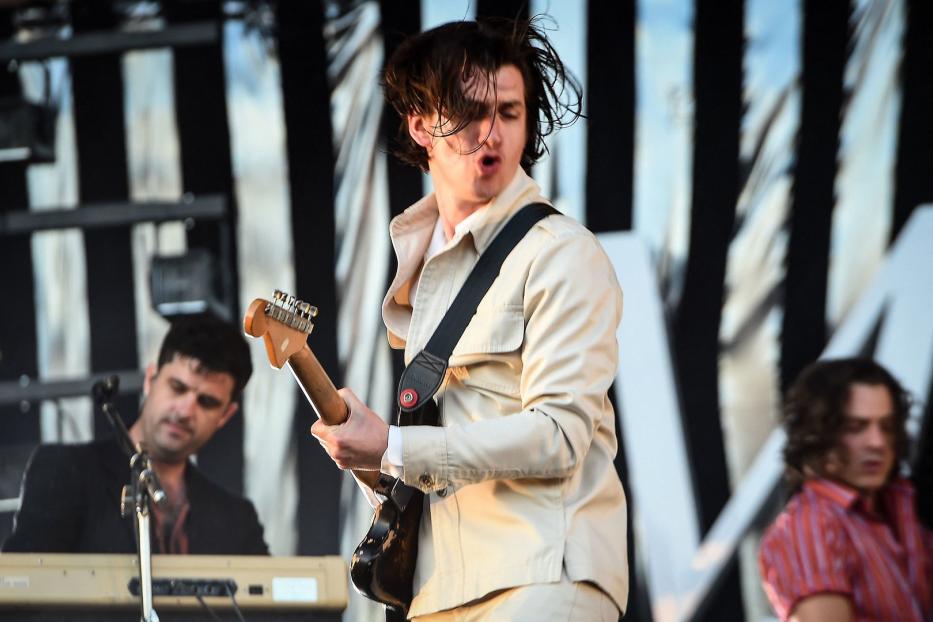 Alex Turner von den Arctic Monkeys spielt Gitarre auf einer Bühne.