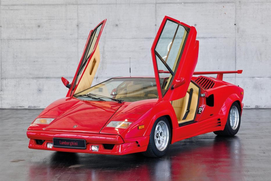 Ein roter Lamborghini Countach mit geöffneten Flügeltüren steht in einem Studio.