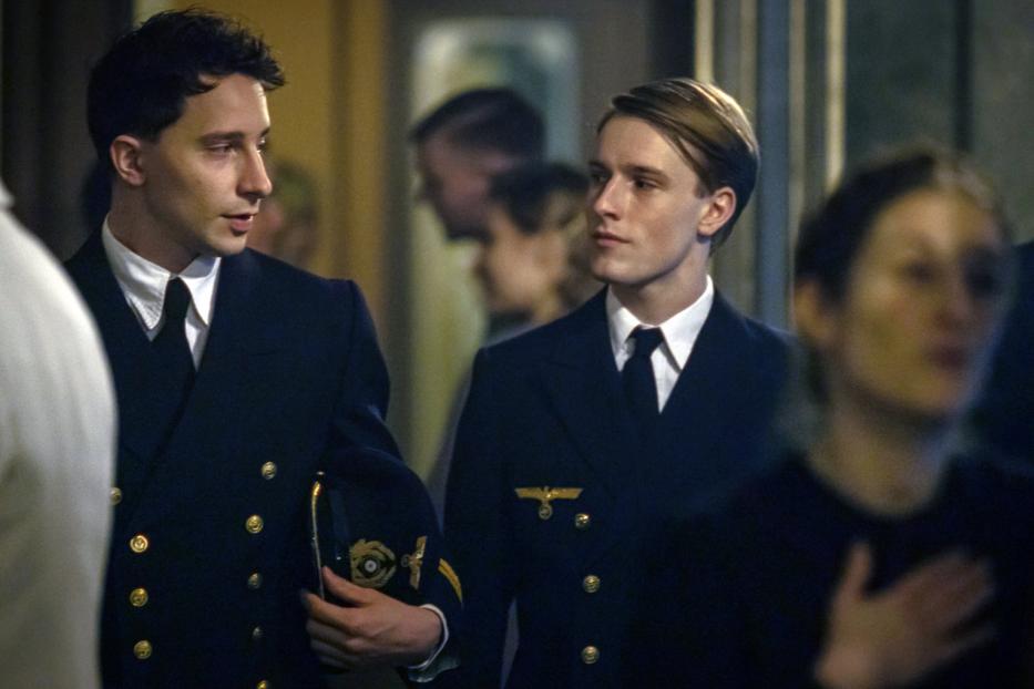 Zwei junge Männer in Marineuniformen stehen in einem Raum.
