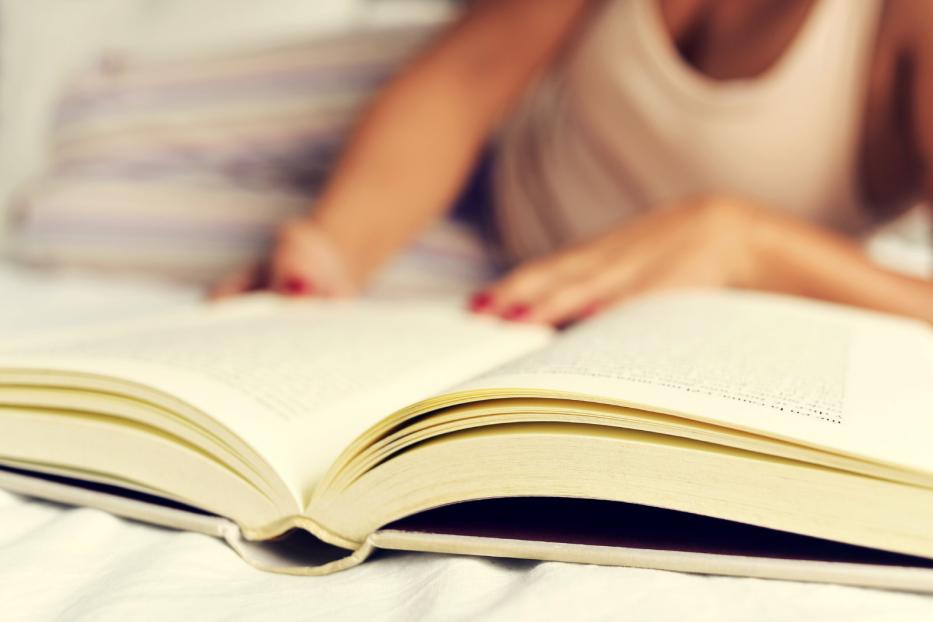 Eine Frau liest ein Buch im Bett.