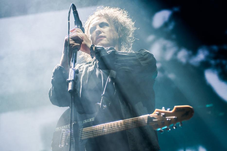 Robert Smith von The Cure singt während eines Konzerts ins Mikrofon.